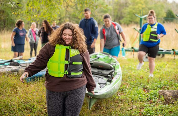 Young lady carrying a kayak